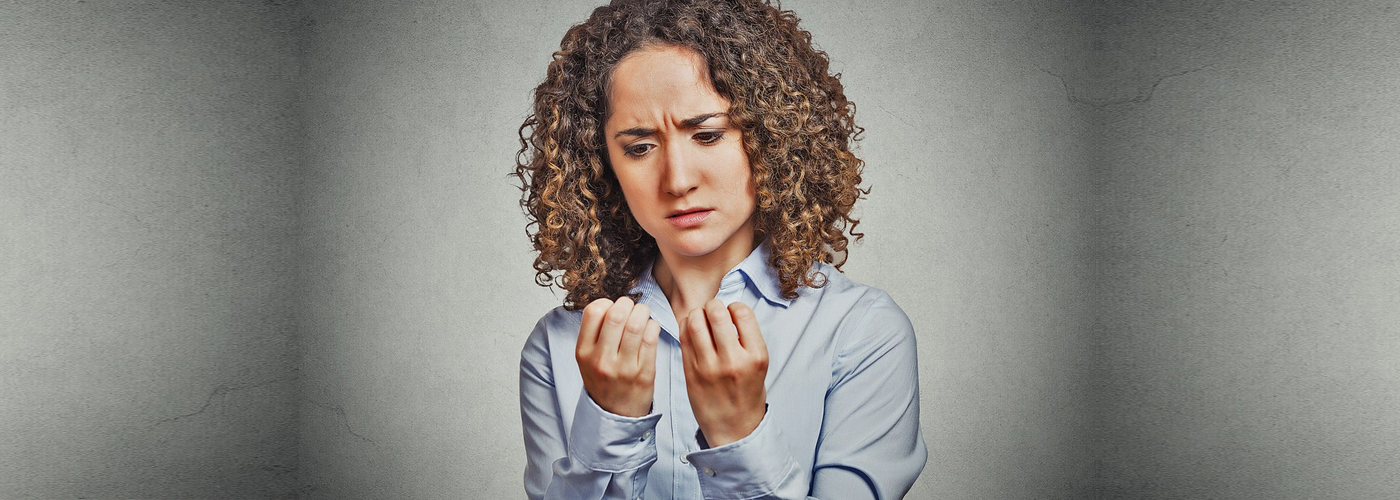 Closeup portrait worried woman looking at hands fingers nails obsessing about cleanliness